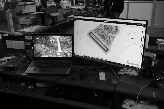 A black and white photo of a desk with two monitors